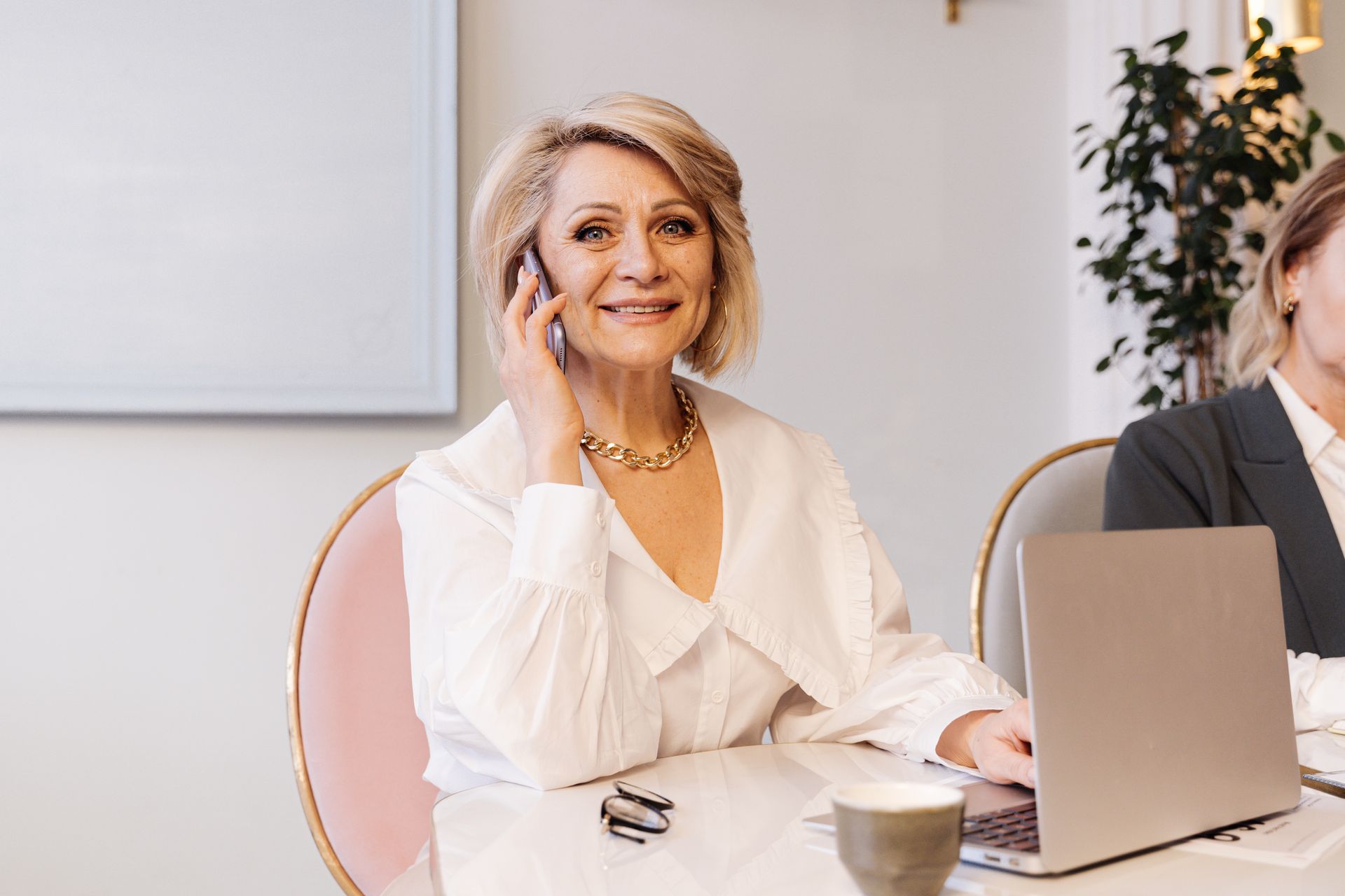 A smiling senior businesswoman on the phone at her desk