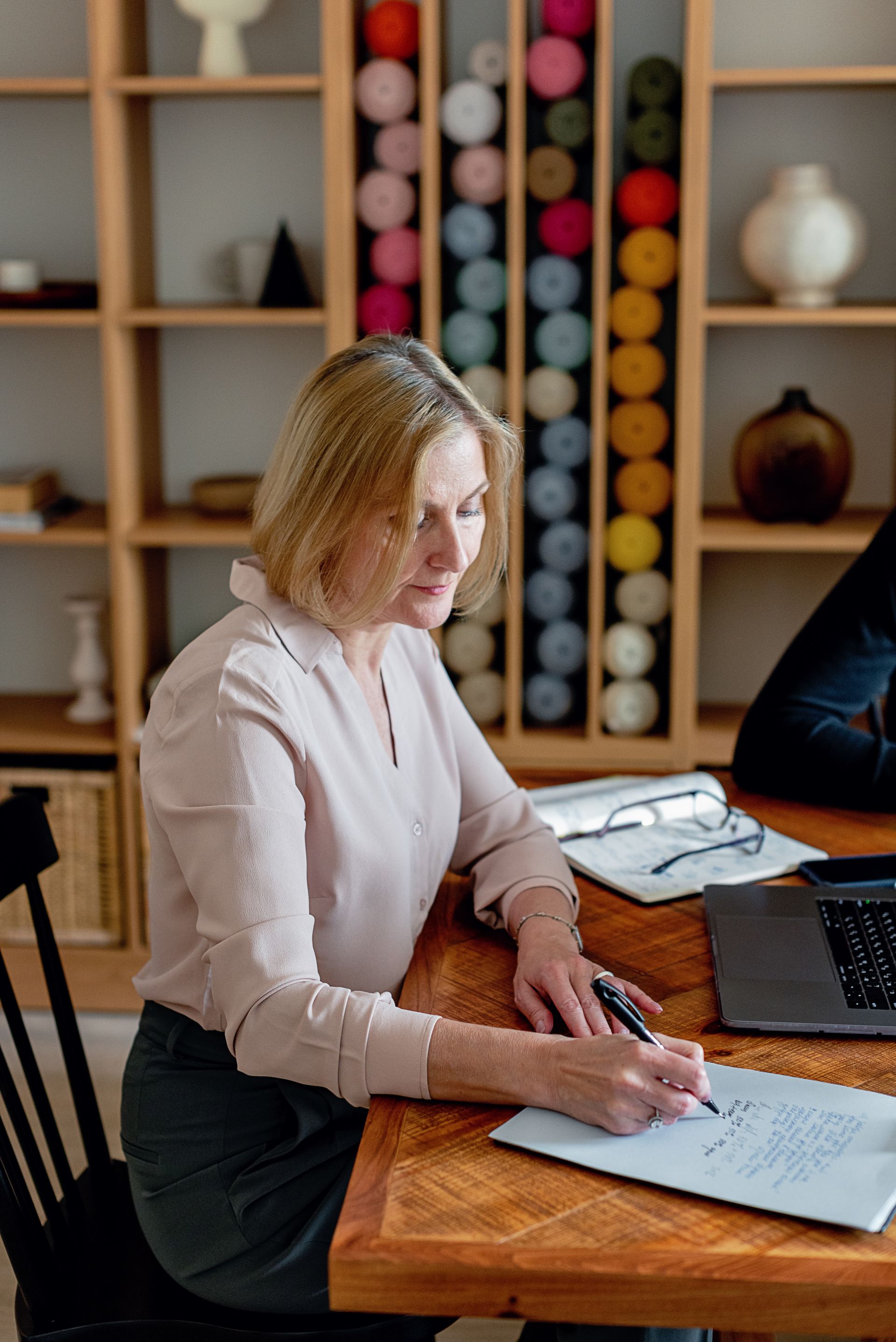 A mature woman writing notes at her desk