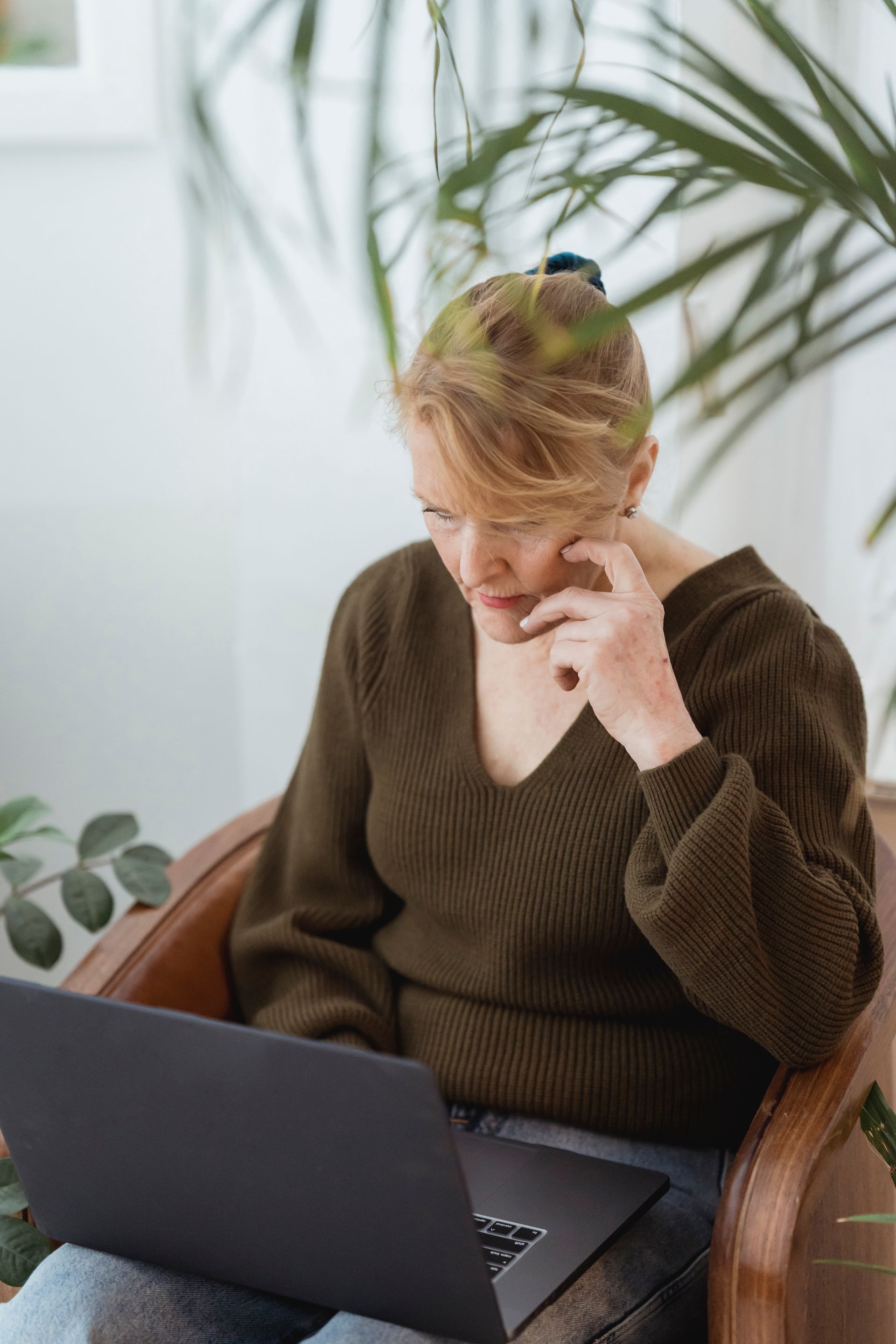A mature woman concentrating on her laptop in an armchair